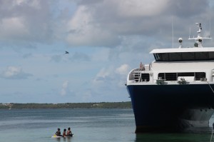 Catamaran dwarfs 3 children on surfboard, Eleuthera, The Bahamas